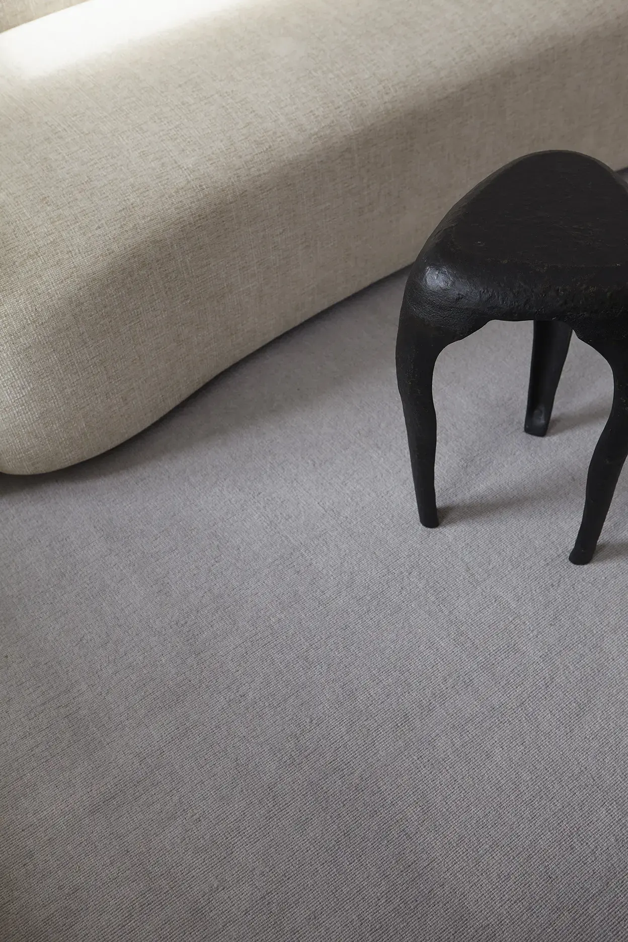 Yuka Misty Sky rug texture close-up with sofa and sculptural stool