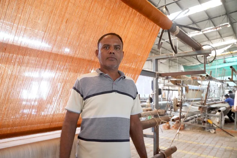 Dablu Master examining a geometric rug pattern at the loom
