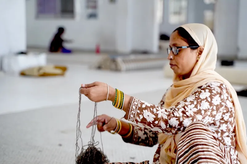 Rajesh Kumar leveling the pile of a cashmere rug in the finishing room