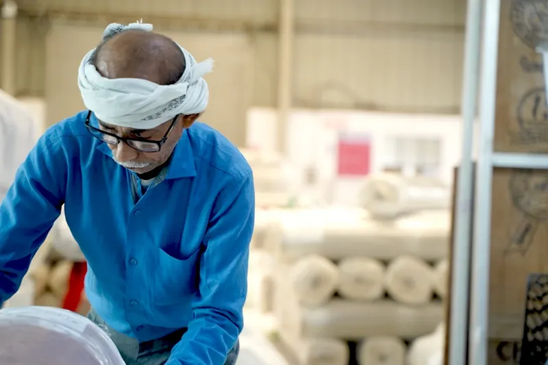 Ram Sevak, master rug weaver, sitting at a traditional loom in Bhadohi